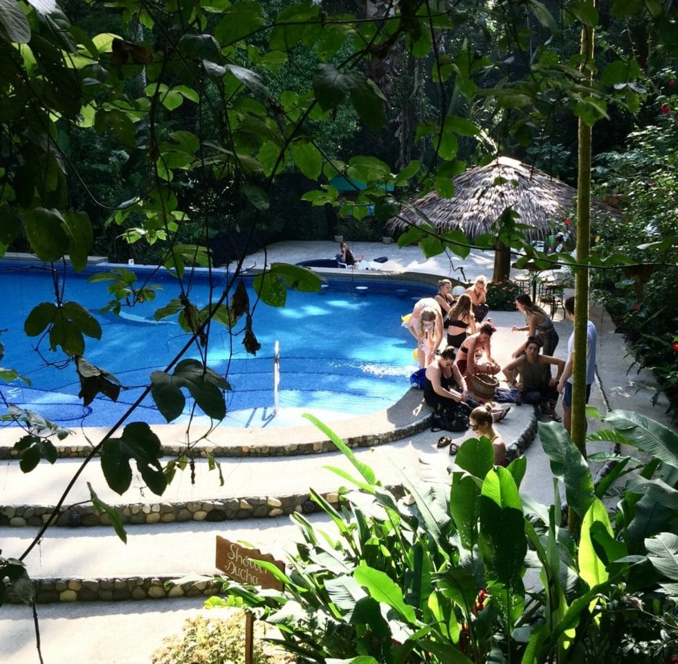 a group of people sitting next to a swimming pool. a group of people sitting next to a swimming pool.