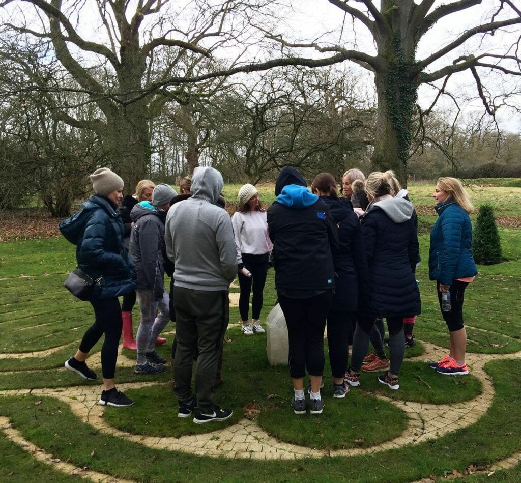 a group of people standing in a circle in a park.