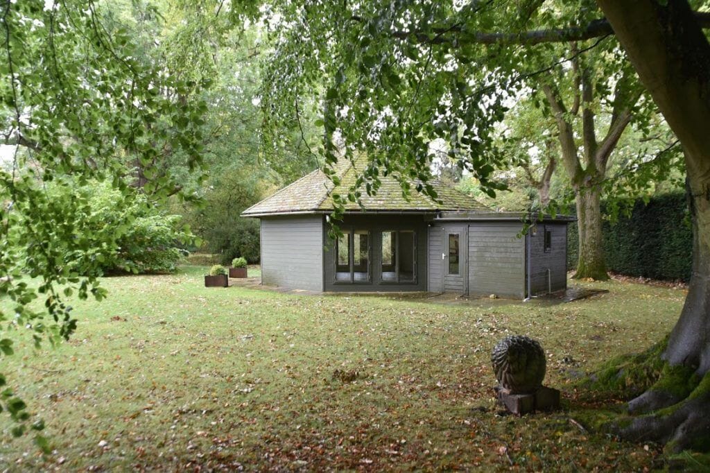 a small gray building sitting in the middle of a forest.