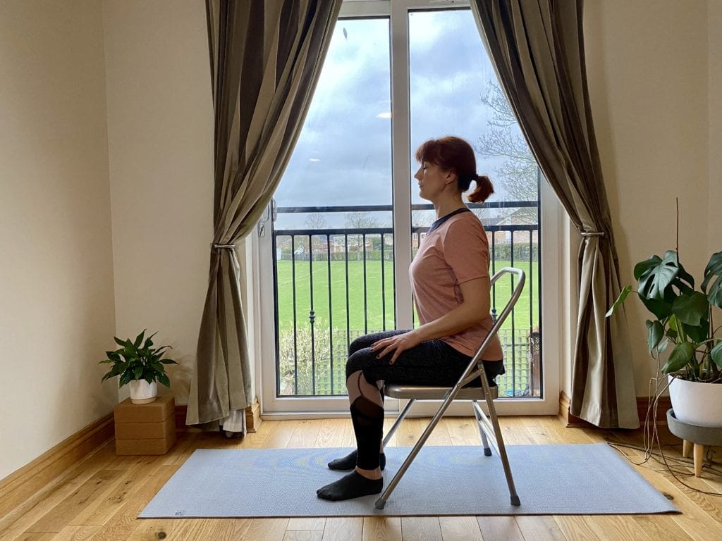 a woman sitting on a chair in front of a window.