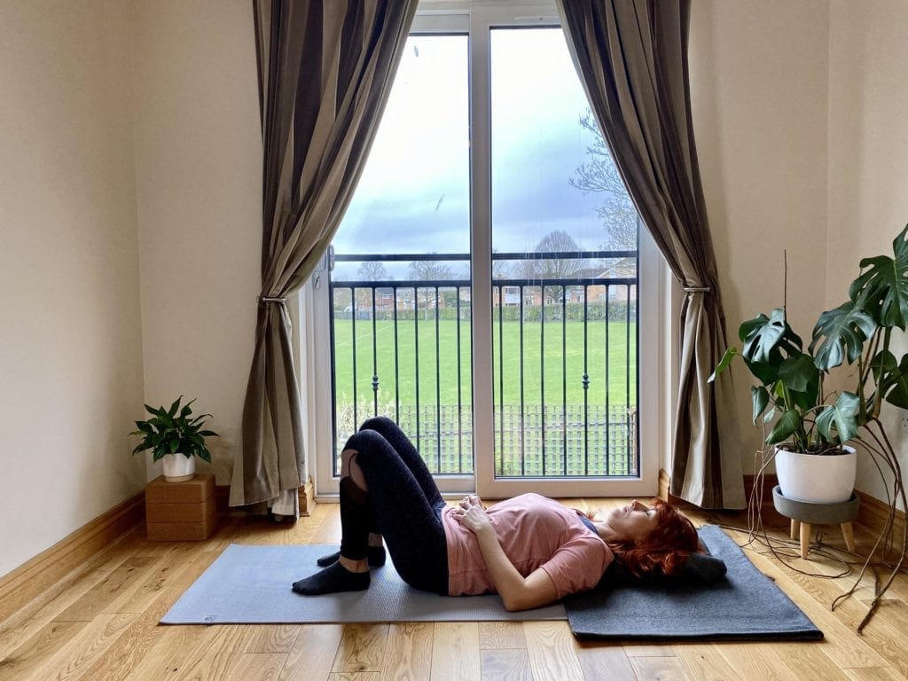 a woman laying on a yoga mat in front of a window.