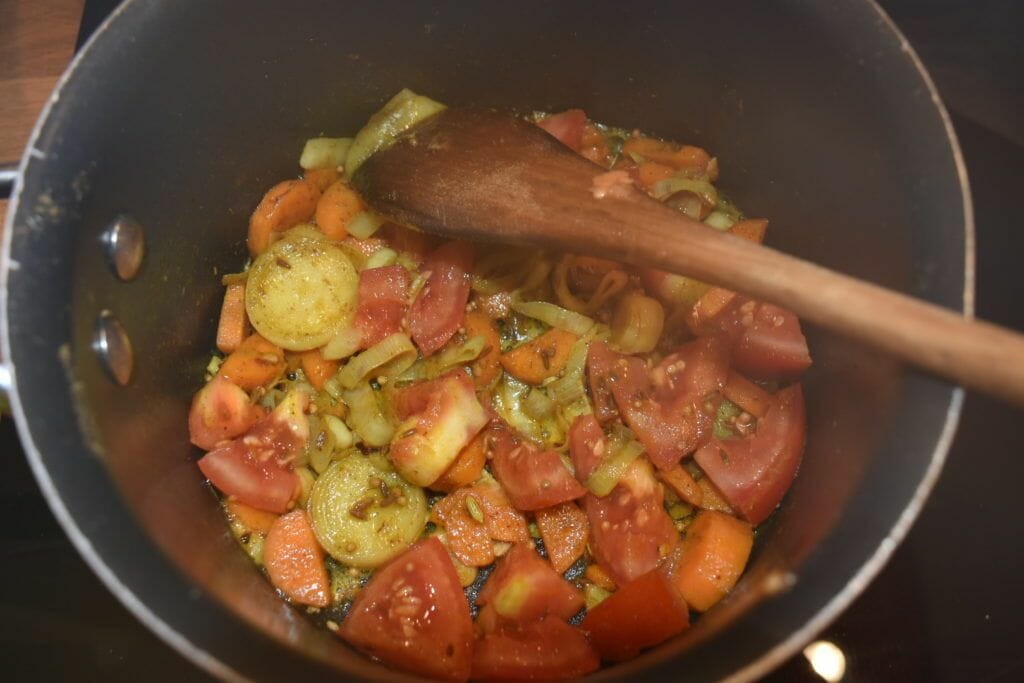 a pan filled with chopped vegetables and a wooden spoon.