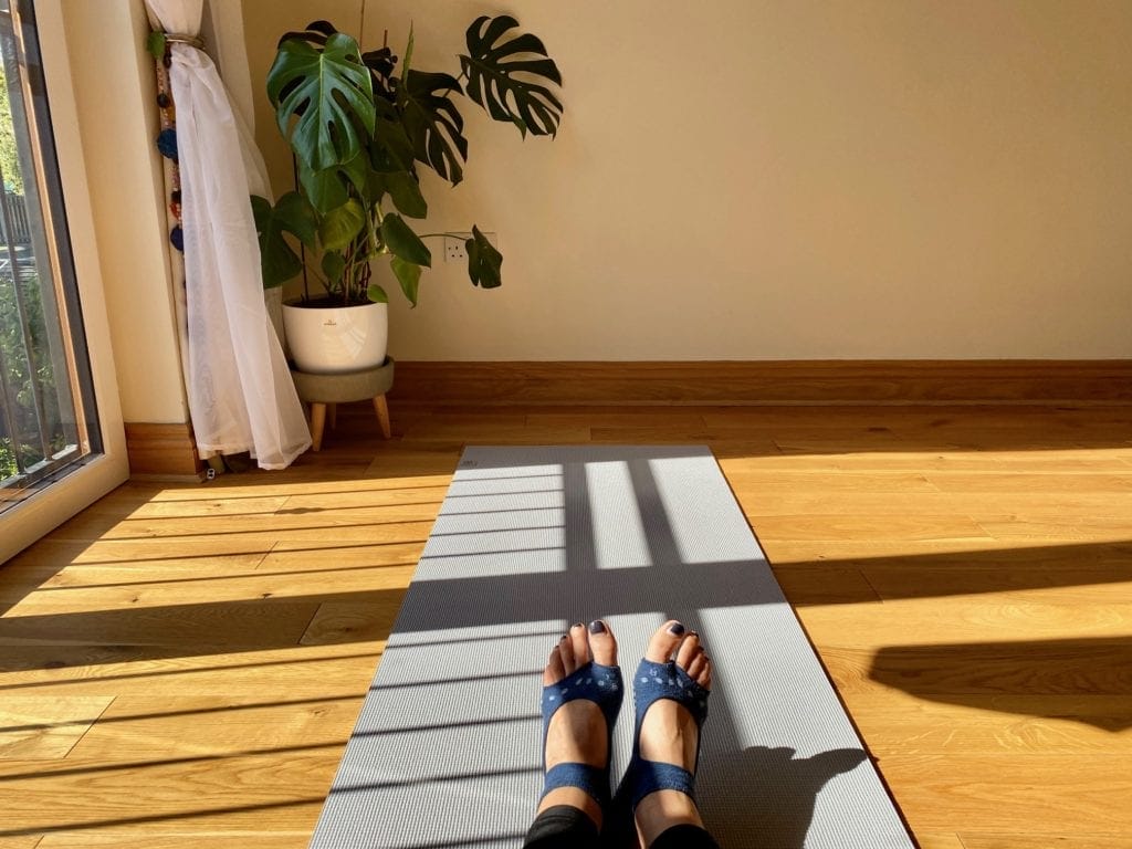 a person sitting on a yoga mat in a room.