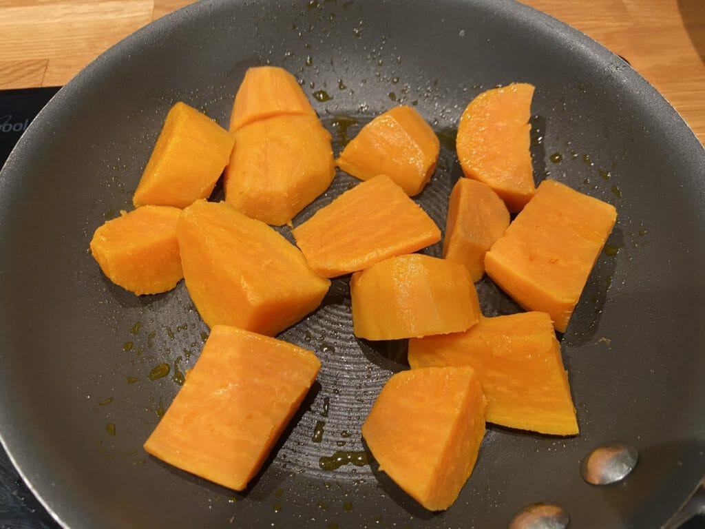 a pan filled with cut up butternuts on top of a stove.