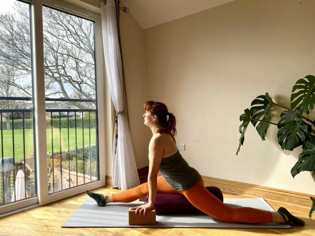 a woman is doing a yoga pose in front of a window.