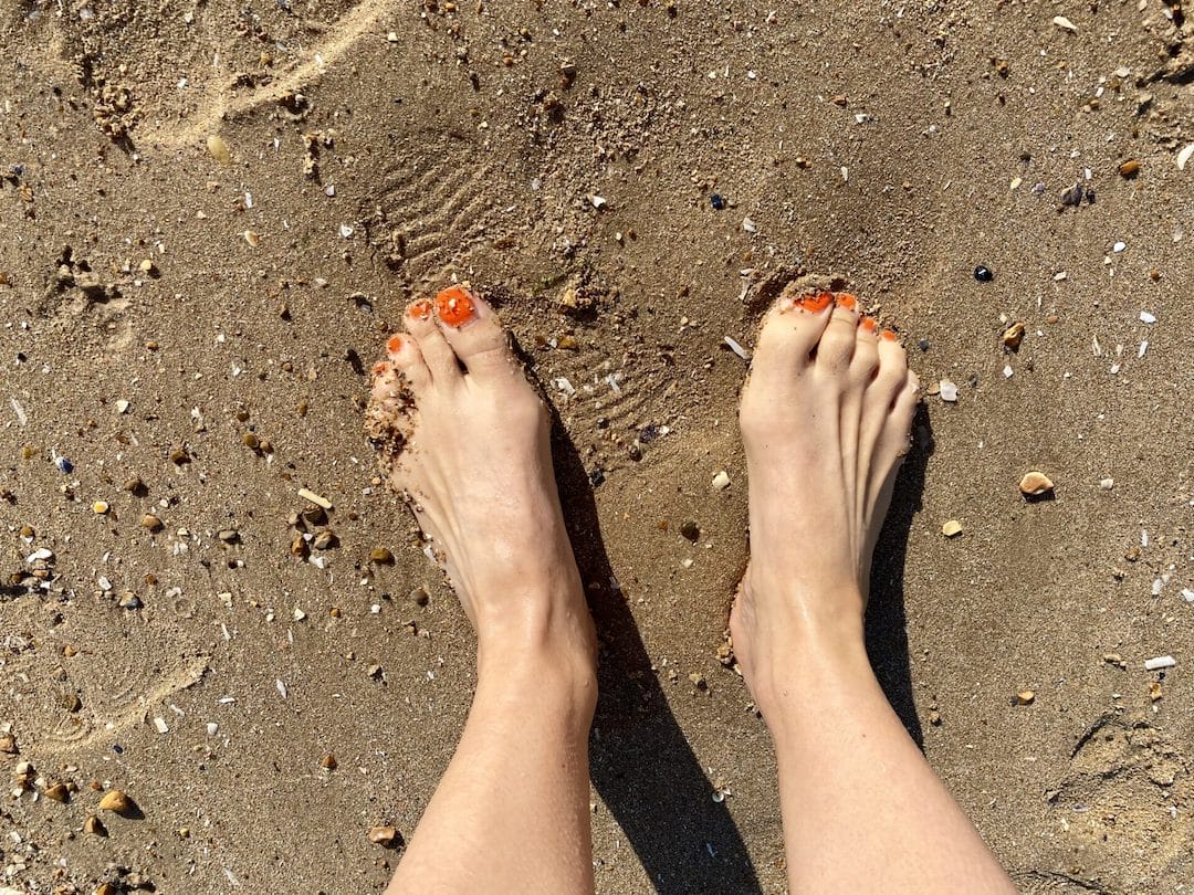 a person standing in the sand with their feet in the sand.