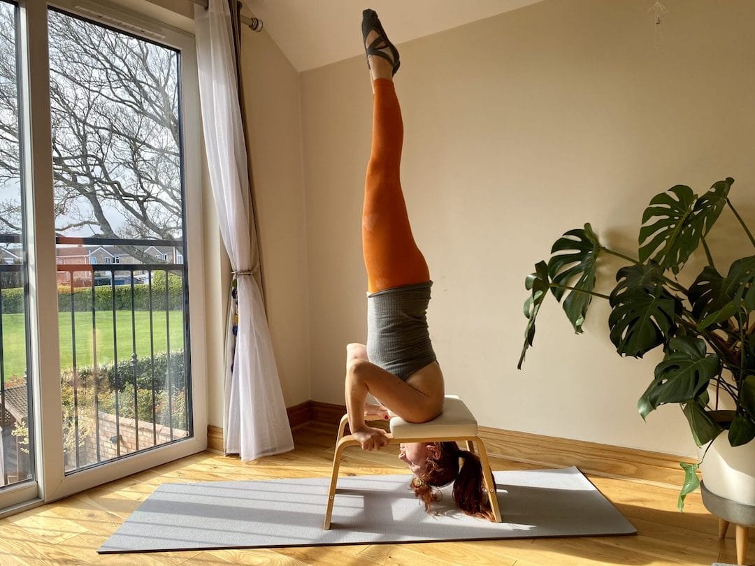 a woman doing a handstand on a yoga mat.