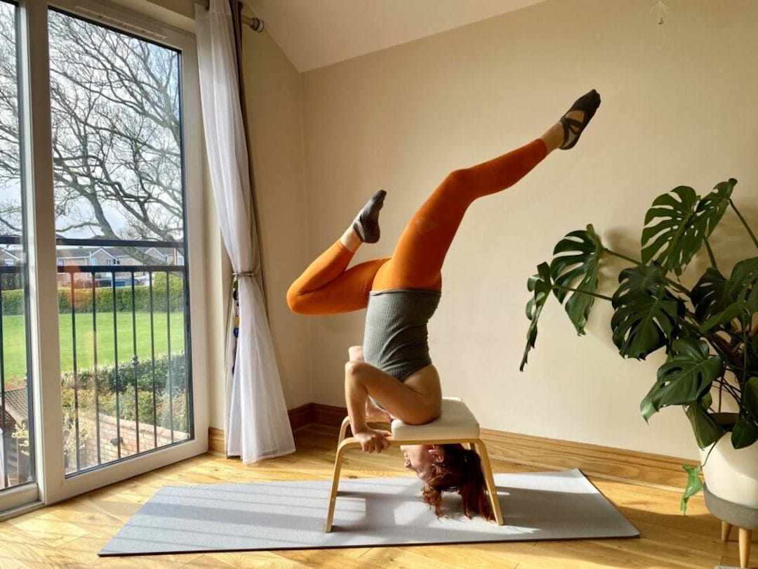 a woman is doing a handstand on a chair. a woman is doing a handstand on a chair.