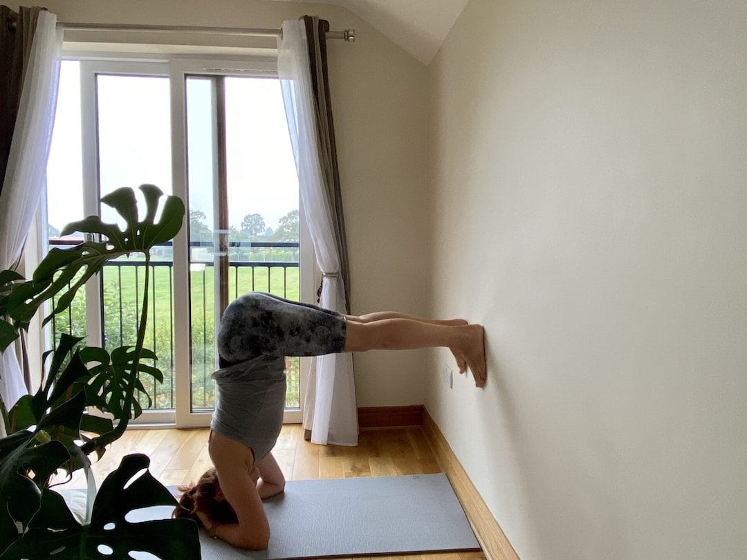 a person doing a yoga pose in front of a window.