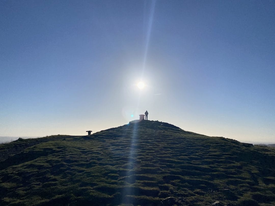 a person standing on top of a grass covered hill.