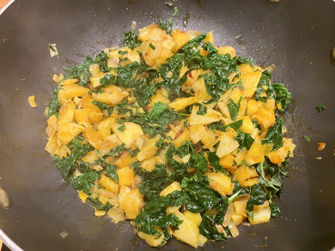 a wok filled with food on top of a wooden table.