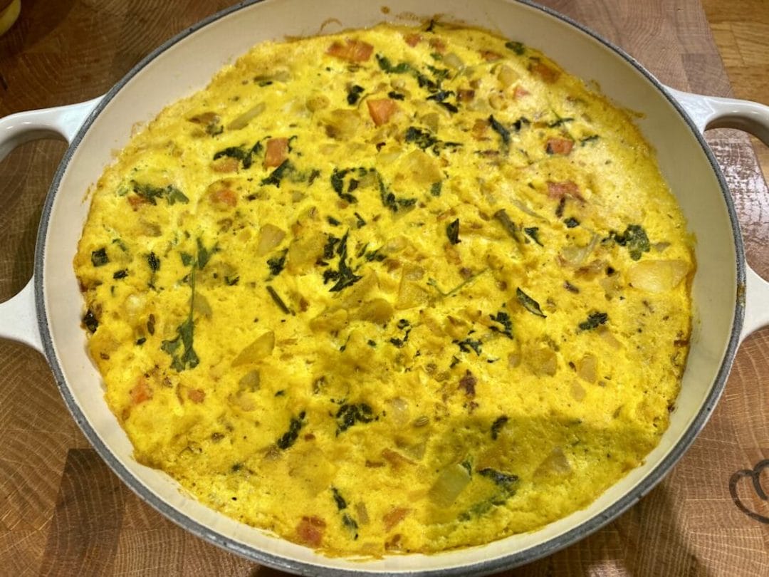 a frittata dish is shown on a wooden table.