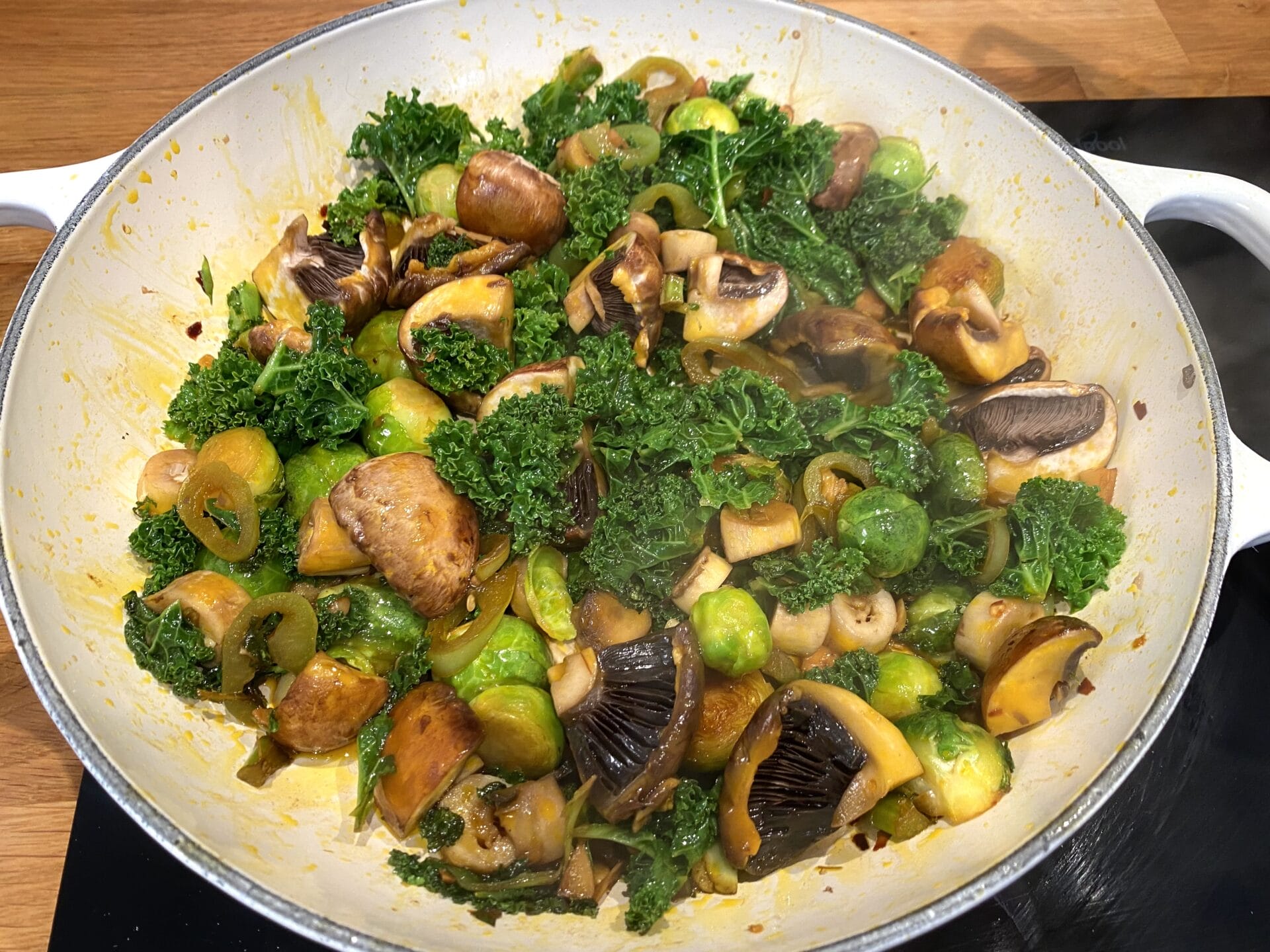 a pan filled with broccoli and mushrooms on a stove.