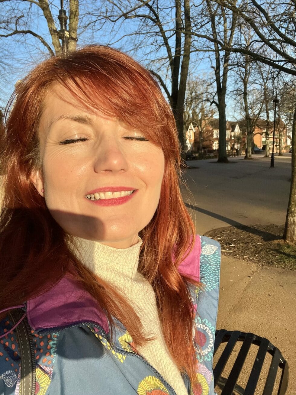 Julia sitting on a bench with her eyes closed.