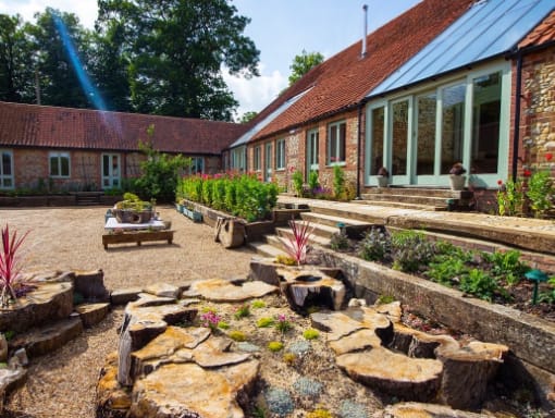 A stone patio with a bench and shrubs at West Lexham