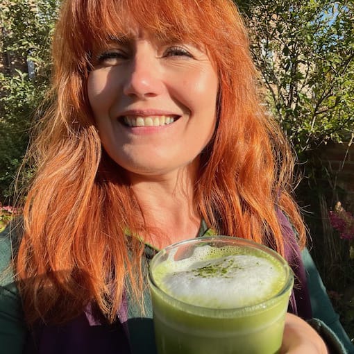 a woman with red hair holding a green drink. Julia with a matcha latte