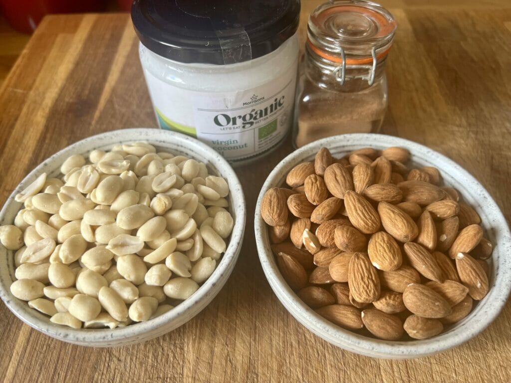 Two bowls of almonds and a jar of almond butter.