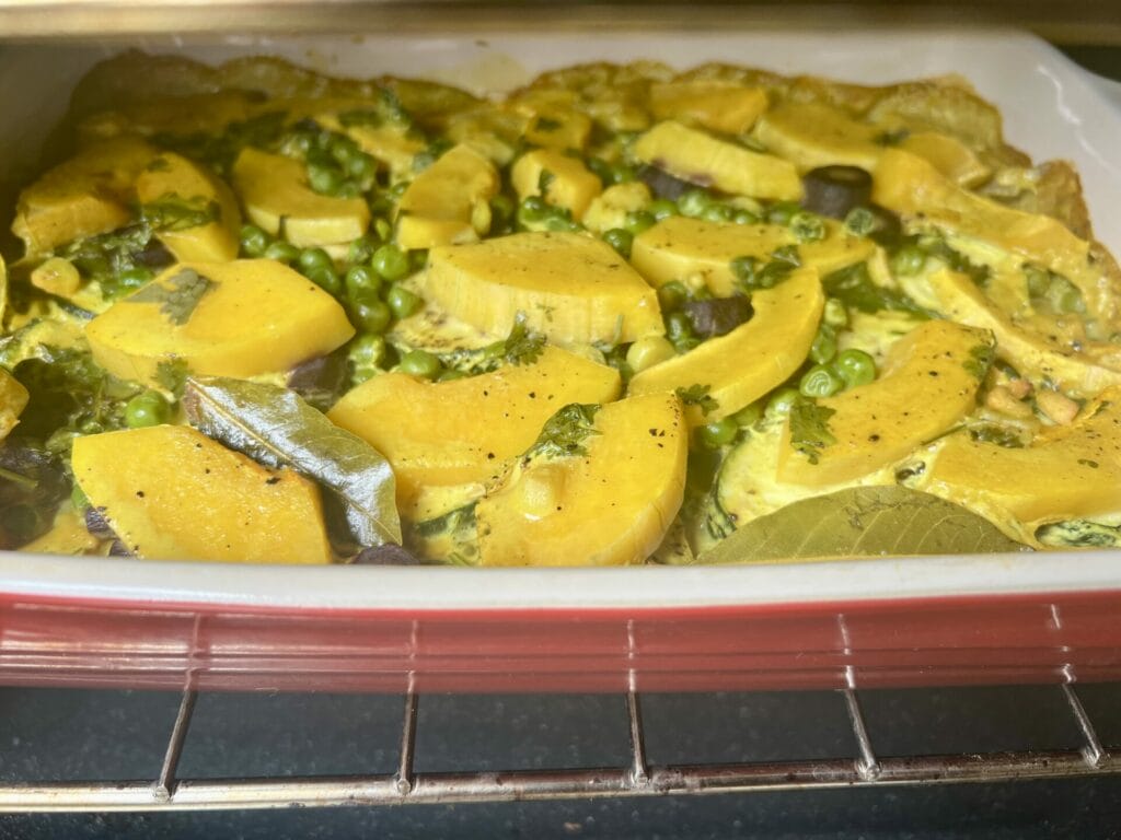 A casserole dish with turmeric-infused butternut squash and vegetables in it.