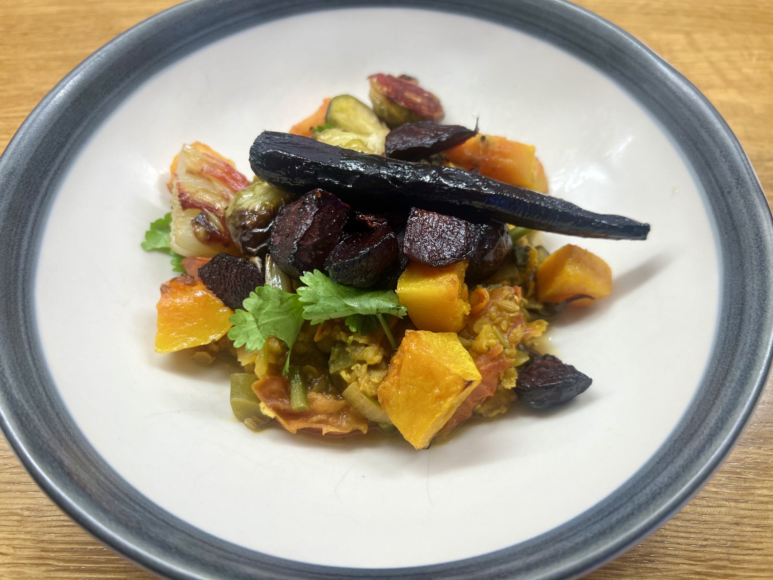 A white plate with a colorful vegetable medley, including roasted carrots, beets, squash, and fresh parsley. A white plate with a colorful vegetable medley, including roasted carrots, beets, squash, and fresh parsley.